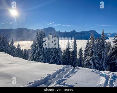 Il sole in un paesaggio montano innevato in Svizzera Foto Stock