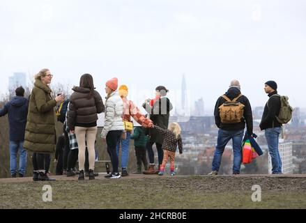 Londra, Regno Unito, dicembre 31st 2021. Le temperature primissime di 15 gradi tentarono un sacco di escursionisti fuori al Parliament Hill Fields a Hampstead Heath nel nord di Londra con vista verso la città. Era ancora nuvoloso dopo uno dei Decembers più nulli dal 1956. Credit: Monica Wells/Alamy Live News Foto Stock