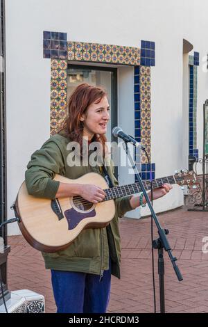 Una musicista folk femminile suona la chitarra all'esterno Foto Stock