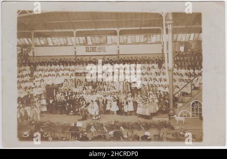 Bournemouth Winter Gardens Pavilion, 1909: Spettacolo di un grande gruppo di bambini, alcuni dei quali sono in abito fantasia (una ragazza sta portando un segno che dice 'voti per le donne'). Un agnello giocattolo sulle ruote è sul lato del palco Foto Stock