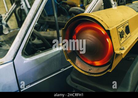 radiatore a gas in un garage meccanico in azione per riscaldare la stanza. Servizio di riparazione. Scatto originale Foto Stock