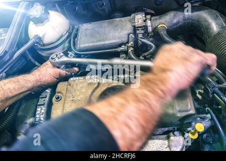 Meccanico automatico che lavora sul motore di un'auto in un garage meccanico. Servizio di riparazione. Primo piano autentico con sfocatura del movimento Foto Stock