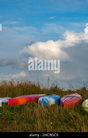 kayak sulla riva pronti per l'uso, fila o fila di kayak di plastica colorati lasciati sulla spiaggia, Foto Stock