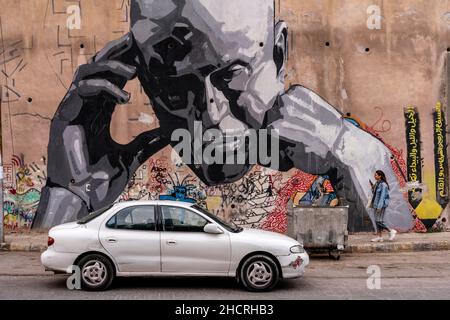 Una giovane donna cammina accanto A Un murale nel centro di Amman, Amman, Giordania. Foto Stock