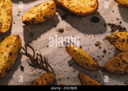 Fette di patate cotte con rosmarino e olio in un forno - verdure biologiche fatte in casa vegano vegetariano patate spicchi pasto snack cibo. Foto Stock