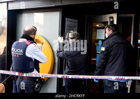 Vendrell, Spagna. 31st Dic 2021. Due agenti del Catalan Police Theft Investigation Group cercano le impronte digitali del rapinatore della banca Caixabank entity.A uomo con un coltello effettua una rapina in un ufficio della banca CaixaBank a El Vendrell (Tarragona Spagna) in fuga con una raccolta ancora da determinare da parte dei responsabili della banca. La polizia catalana indaga sulla scena della rapina e cerca le impronte digitali del rapinatore Credit: SOPA Images Limited/Alamy Live News Foto Stock