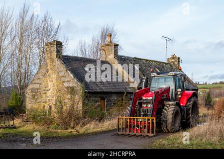 BALLINDALLOCH, MORAY, SCOZIA - 30 DICEMBRE 2021: Si tratta di un moderno trattore Massey ferguson parcheggiato accanto a una vecchia fattoria disutilizzata a Ballindalloch, Foto Stock