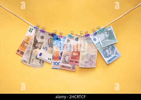 Banconote di diverse valute internazionali appese su una corda Foto Stock