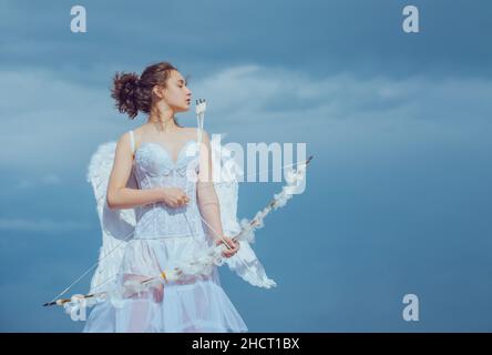 Teen Cupid in abito angeli bianchi, giorno di San Valentino con arco freccia tiro. Angelo adolescente con angeli ali. Foto Stock