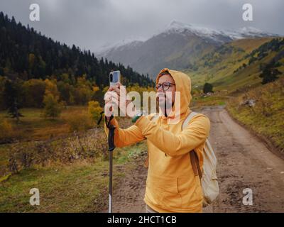 L'uomo crea splendide foto sullo smartphone per i social network. Stile di vita vagante, concetto di avventura vacanza autunnale all'aperto, da solo in natura. Viaggia verso il Caucaso settentrionale, Arkhyz, Russia Foto Stock