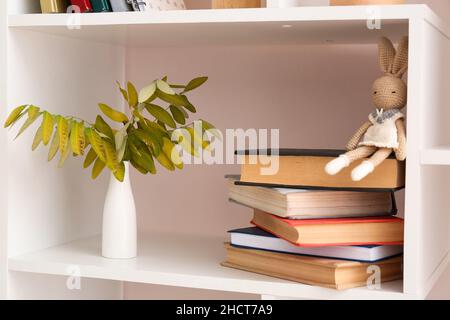 Pila di libri e vaso con rami autunnali su scaffale Foto Stock