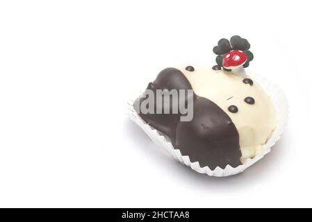 Primo piano del dolce dessert a forma di ferro di cavallo con funghi fortunati e quattro foglie di trifoglio su di esso come fascino fortunato per Capodanno isolato su dorso bianco Foto Stock