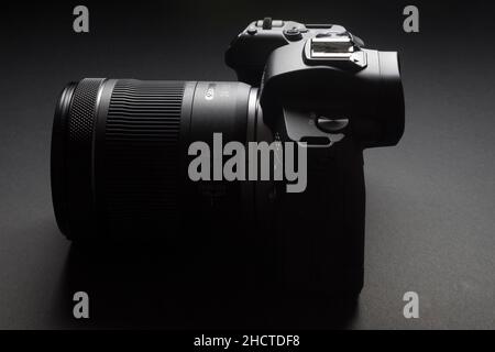 Milano, Italia - 1 gennaio 2022: Primo piano su Canon EOS R mirrorless fotocamera appoggiata su sfondo nero e scattata con la pittura chiara, nessuna gente è vi Foto Stock