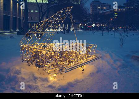 Novosibirsk, Russia, 18 dicembre 2021: Scultura di pianoforte illuminata nella piazza vicino al teatro accademico di opera e balletto Foto Stock