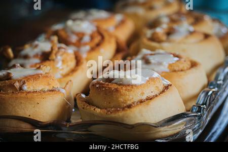 Primo piano di dolce cremoso rotolo di cannella fatto in casa servito in un tavolo di vetro Foto Stock