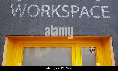 Cartello area di lavoro verniciato su sportello giallo in ferro. Adesivo cani vietati sull'angolo destro Foto Stock