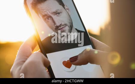 App di incontri sullo schermo del telefono cellulare. Donna che passa e ama i profili sul sito di relazione o applicazione. Donna singola che usa lo smartphone per trovare l'amore, Foto Stock