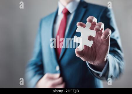 Uomo d'affari che tiene un puzzle per connettersi Foto Stock