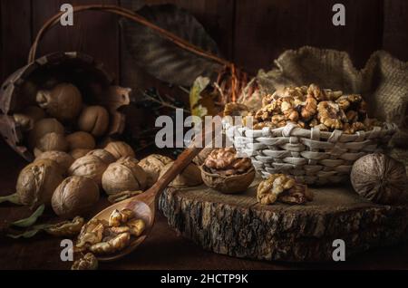 noci e nocciole in un cestino su sfondo di legno scuro Foto Stock