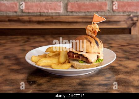 Burger con bacon avvolto con gamberi, salsa rosa e fritte francesi Foto Stock