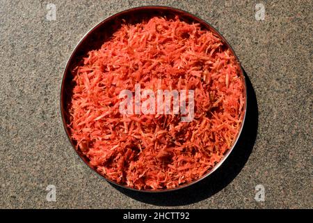 Preparazione di verdure di carota grattugiate fresche per preparare ricette di carota come gajar ka halwa. Carota grattugiata in piatto Foto Stock