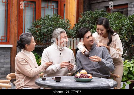 Famiglie felici che bevono il tè e chiacchierano nel cortile Foto Stock