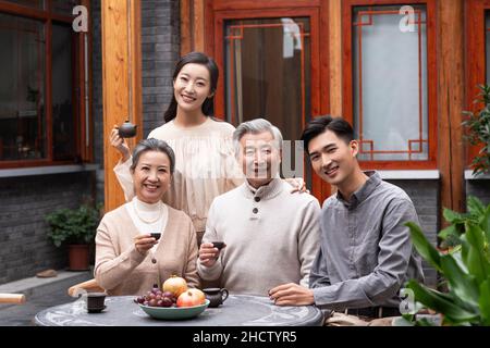 Famiglie felici che bevono il tè e chiacchierano nel cortile Foto Stock