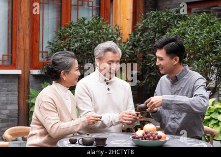 Famiglie felici che bevono il tè e chiacchierano nel cortile Foto Stock