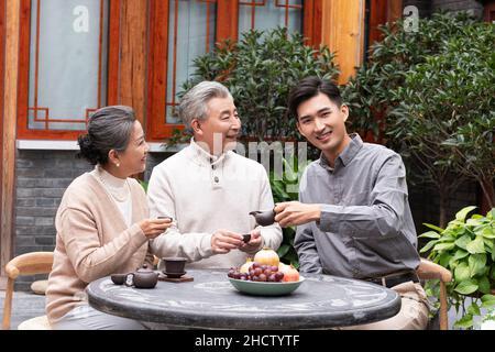 Famiglie felici che bevono il tè e chiacchierano nel cortile Foto Stock