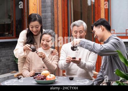 Famiglie felici che bevono il tè e chiacchierano nel cortile Foto Stock