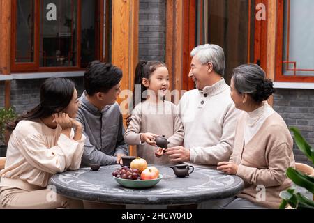 Famiglie felici che bevono il tè e chiacchierano nel cortile Foto Stock