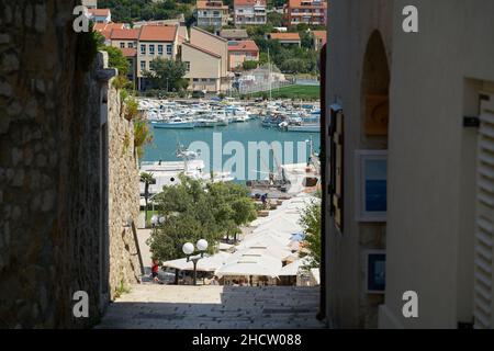 Vista attraverso un vicolo stretto fino al porto della città di Rab in Croazia Foto Stock