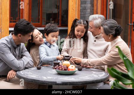 Famiglie felici che bevono il tè e chiacchierano nel cortile Foto Stock