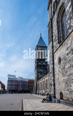 Lund, Svezia - Maggio 1 2021: Persone sedute lungo le mura della cattedrale godendosi il primo sole primaverile Foto Stock