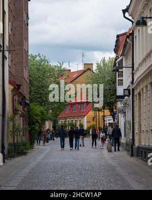 Lund, Svezia - Maggio 22 2021: Persone che camminano su strade acciottolate storiche nelle parti antiche della città universitaria Foto Stock