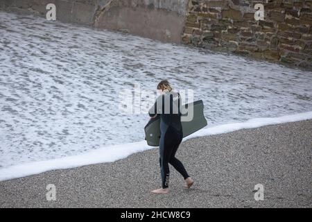 Portreath, Cornovaglia, 1st gennaio 2022, grandi onde e mari tempestosi a Portreath, Cornovaglia causata da forti venti Sud Westerly questa mattina. Un surfer entra nelle onde il giorno di Capodanno, sperando di un anno migliore di quello dell'anno scorso. La temperatura era di 13C che è mite per il periodo dell'anno. La previsione è di essere venti gustosi per oggi che si calmerà questa sera.Credit: Keith Larby/Alamy Live News Foto Stock