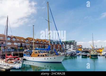 Barche a vela ormeggiate da appartamenti sul mare a Camber Quay nel porto di Portsmouth, Hampshire, costa sud Inghilterra Foto Stock