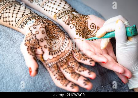 Le mani della donna o della sposa sono decorate in mehndi, una forma di arte del corpo e decorazione temporanea della pelle disegnata solitamente sulle mani o sulle gambe. Foto Stock