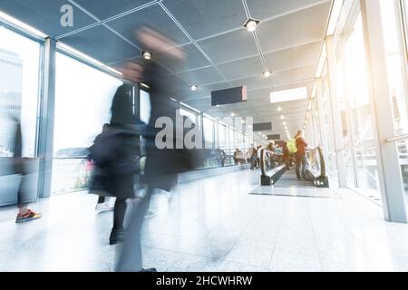 Molti anonimo sfocata persone andare in aeroporto o in una fiera commerciale Foto Stock