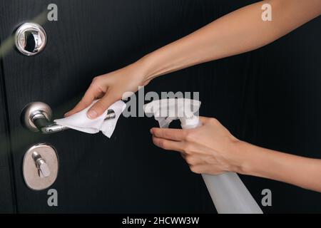 Pulizia delle maniglie nere delle portiere con una salvietta antisettica bagnata e spray igienizzante. Disinfezione in ospedale e spazi pubblici contro il virus corona. Donna Foto Stock