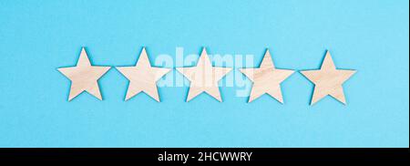 Cinque stelle su uno sfondo colorato, mano mettere l'ultima stella in fila, la valutazione, dando feedback Foto Stock
