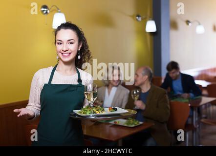 La cameriera accoglie i clienti al tavolo Foto Stock