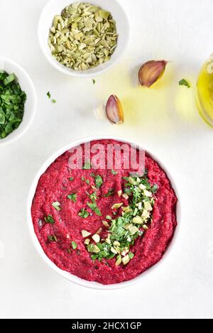 Hummus di barbabietola fatto in casa in ciotola su sfondo di pietra bianca. Vista dall'alto, disposizione piatta Foto Stock