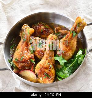 Vista ravvicinata dei bastoncini di pollo cotti con mele ed erbe in padella. Foto Stock