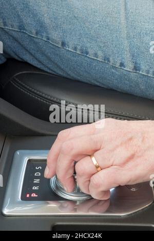 Una donna che utilizza il selettore del cambio in un'auto automatica, in questo caso una Land Rover Discovery. Foto Stock