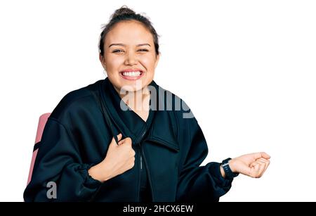 La giovane ragazza ispanica che tiene il tappeto yoga urlando orgoglioso, celebrando la vittoria e il successo molto eccitato con braccio sollevato Foto Stock