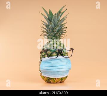 Interpretazione della frutta di ananas in forma umana durante una pandemia con occhiali e una maschera di protezione medico. Spazio di copia Foto Stock