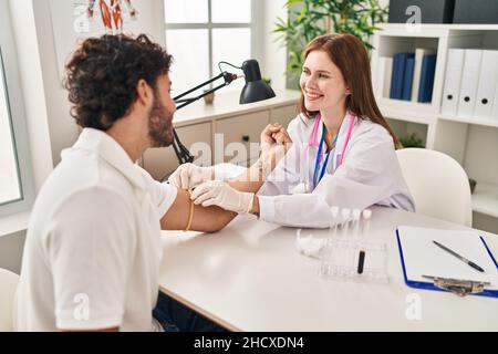 L'uomo e la donna che indossano l'uniforme del medico che hanno analisi del sangue in clinica Foto Stock
