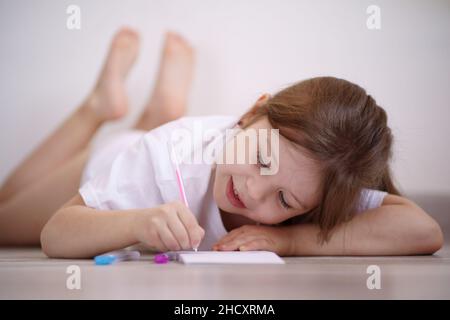 La bambina si trova sul pavimento e si disegna Foto Stock