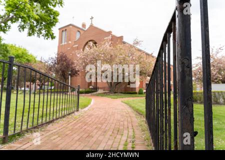 Una chiesa generica vista attraverso i pali di recinzione di acciaio lungo il disegno paesaggistico bello. Fotografia di concetto esterno di giorno Foto Stock